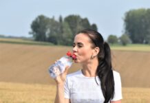 물의 중요성 a woman standing in a field drinking from a bottle
