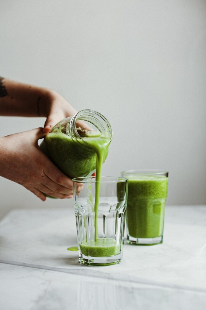 Photo by Alex Lvrs person holding clear drinking glass with green liquid