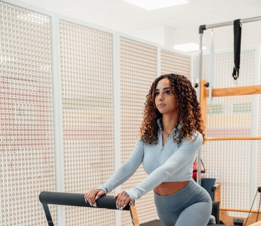 필라테스, 몸과 마음을 동시에 건강하게 하는 비결 a woman in a gray top and leggings is on a rowing machine