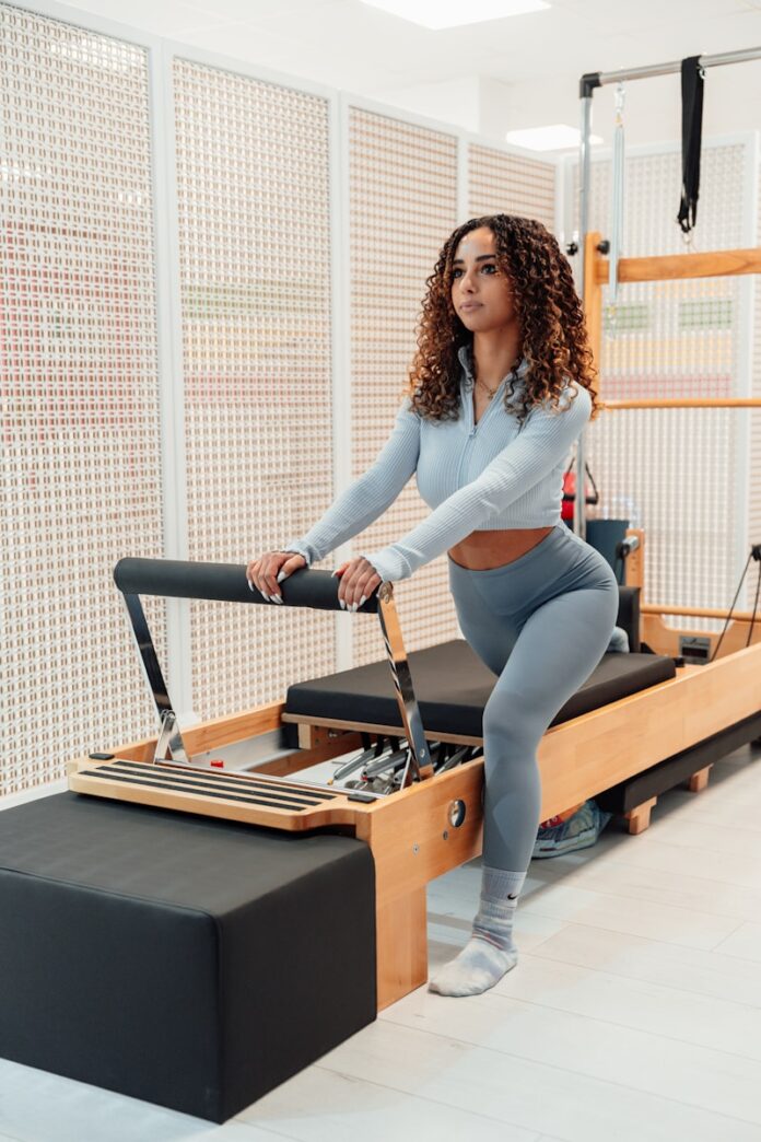 a woman in a gray top and leggings is on a rowing machine