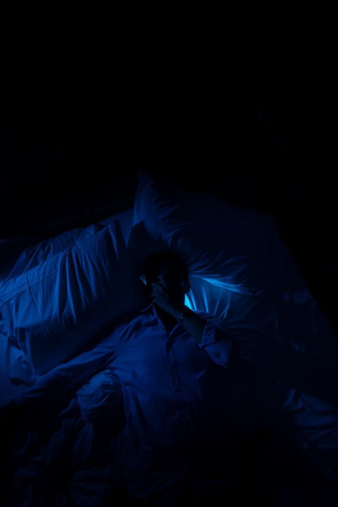 A person laying in a bed in a dark room