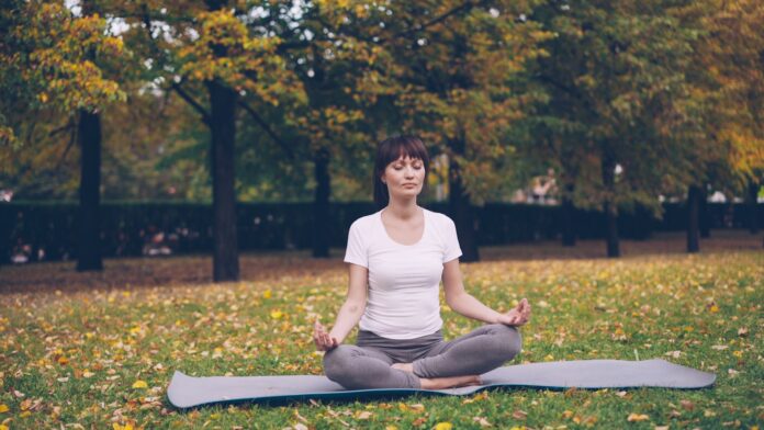 Photo by Vitaly Gariev Woman meditating in a park during autumn.