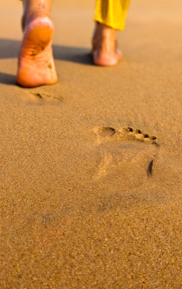 Footprints on a sandy beach leading away