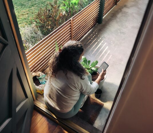 만성피로의 그늘, 일상 속 실천으로 밝게 걷자 Woman sitting on balcony with smartphone