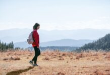 일상 속 ‘마음챙김 걷기’, 건강과 힐링을 한 번에 a man with a backpack walking across a dry grass covered field